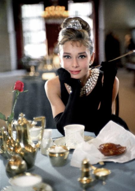 Audrey Hepburn posing at a dining table in her iconic Breakfast at Tiffany's costume