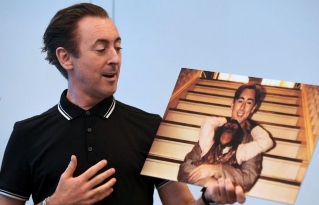 Alan Cumming holding a photograph of him and Tonka the chimpanzee