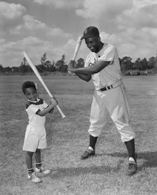 Photo of Jackie Robinson and his son holding baseball bats