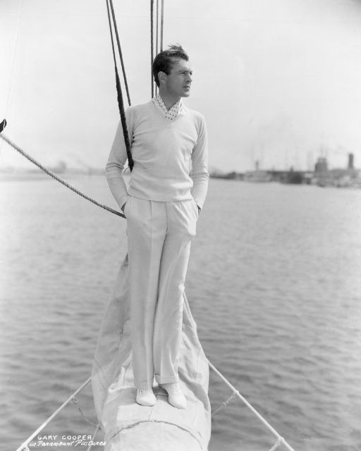 Photo of Gary Cooper standing on the prow of a sailboat.
