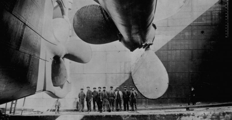 Shipbuilders gather underneath one of the Titanic's propellers (1912). Before