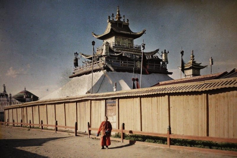 An orange-robed monk walks past a temple in what was called Khuree and is now Ulaanbaatar, the capital of Mongolia