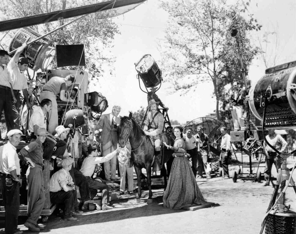 Crew filming Peachtree Street scene; director Victor Fleming works with Vivien Leigh as Scarlett O'Hara and William Bakewell as mounted Officer.