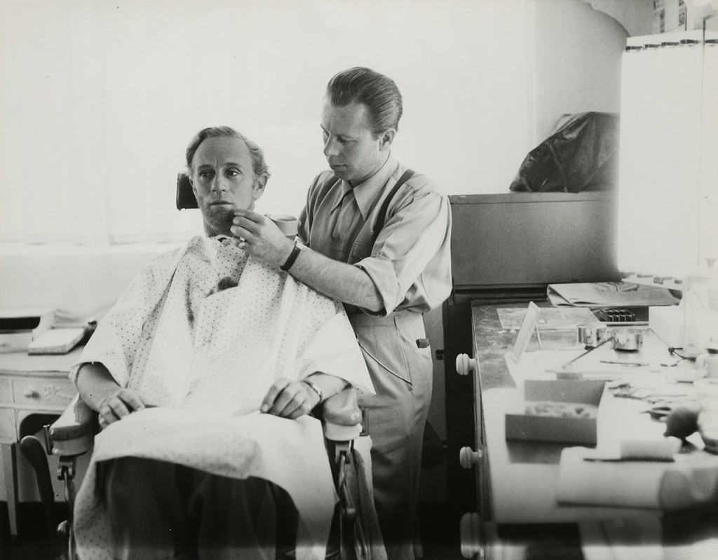 Make up artist Monte Westmore applies make up to actor Leslie Howard in the role of Ashley.