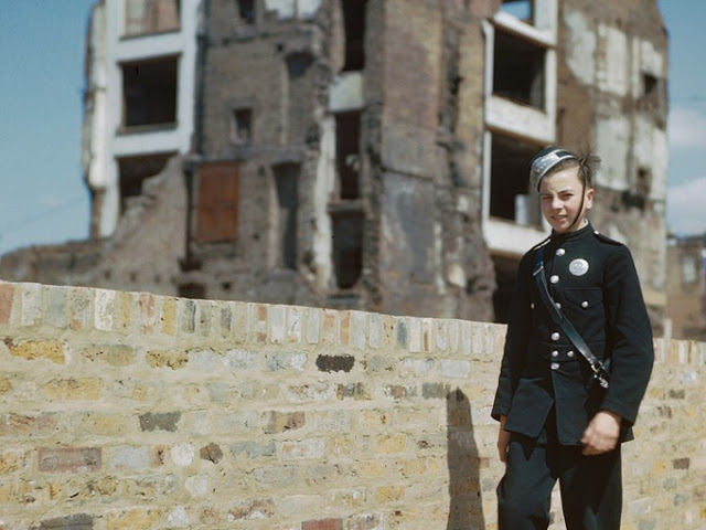 A London messenger boy walking past a bomb site in London.