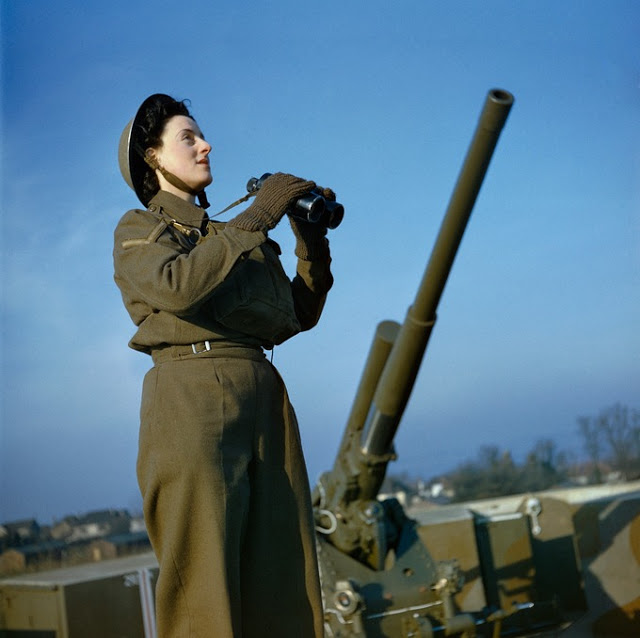 ATS spotter with binoculars at the anti-aircraft command post, with a 3.7 inch anti-aircraft gun in the background