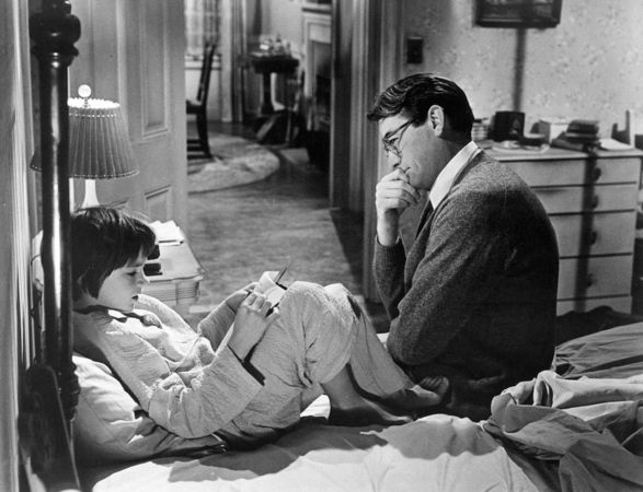 Scout reads a book while Atticus Finch listens