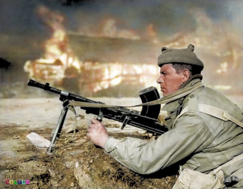 Private J. Oates 'B' Company 1st Battalion Argyll and Highland Sutherlands, 27th Brigade getting ready to fire his Bren Gun at a sniper, with a blazing house in the background. (possibly at Chongju, 30 October 1950) "The 1st Battalion led the advance on the 28th (Oct.) with its leading platoon mounted on tanks. The main opposition came from tanks, and this imposed long delays on the column, although the air gave all support that could be desired, frequently spotting and destroying tanks in the path of the Battalion. These delays made it impossible to reach Chongju in daylight, and the Battalion halted for the night about a mile away, and it was fortunate it did so as there turned out to be a strongly held and well-sited position defending the town. The following day 3rd Battalion, Royal Australian Regiment (3 RAR) encountered stubborn resistance, which took the greater part of the day to overcome, but by the evening all was set for the entry to Chongju, which was to take place the following morning, 30th October". (argylls1945to1971.co.uk) (Colourised by Royston Leonard from the UK) https://www.facebook.com/pages/Colourized-pictures-of-the-world-wars-and-other-periods-in-time/182158581977012 
