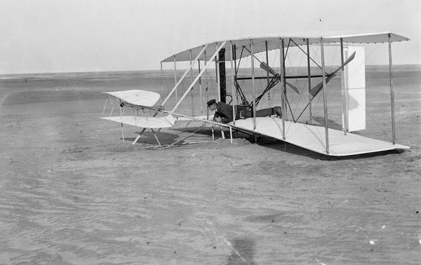 Wilbur Wright at the controls of the damaged Wright Flyer, on the ground after an unsuccessful trial on December 14, 1903, in Kitty Hawk, North Carolina.