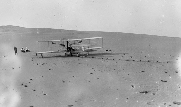 The remodeled 1905 Wright machine, altered to allow the operator to assume a sitting position and to provide a seat for a passenger, on the launching track at Kill Devil Hills in 1908.