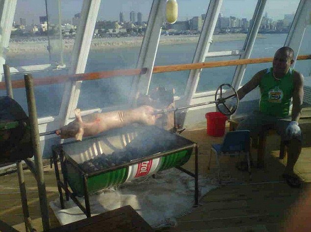 Workmen are pictured roasting a pig on a makeshift barbecue on one of the decks of the iconic liner. The Queen Elizabeth II has been left to rot in a Dubai dockyard after plans to transform it into a hotel stalled 