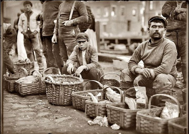 Boy selling fish from a basket in Boston street market, October 1909