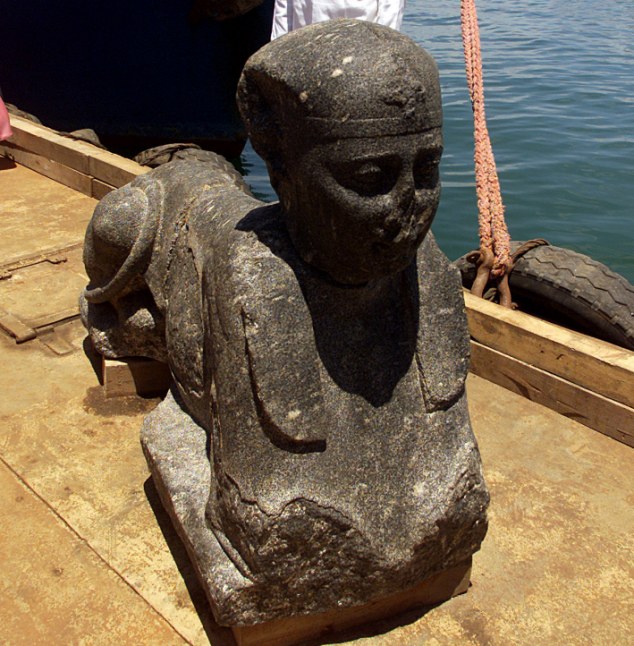 Egyptian naval security stands guard behind a statue of an ancient sphinx as it sits on a barge in an Alexandria naval base June 7, 2001. Statues, sunken ships, gold coins and jewelry are among the submerged treasures that French Marine archaeologist Frank Goddio has uncovered in the ancient submerged city of Heracleion off the coast of Alexandria. source 