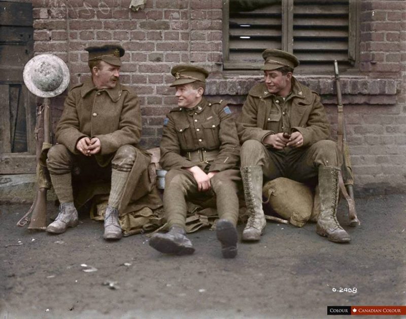 Pte. T.W. Holmes, V.C. (centre), 4th Canadian Mounted Regiment, 21 Jan 1918 Holmes was 19 years old, when as a private serving with the 4th Battalion, Canadian Mounted Rifles, Canadian Expeditionary Force, he won the Victoria Cross. On 26 October 1917 near Passchendaele, Belgium, he performed a deed for which King George V awarded Tommy the Victoria Cross: "when the right flank of the Canadian attack was held up by heavy machine-gun fire from a pill-box strong point and heavy casualties were producing a critical situation, Private Holmes, on his own initiative and single-handed, ran forward and threw two bombs, killing and wounding the crews of two machine-guns. He then fetched another bomb and threw this into the entrance of the pill-box, causing the 19 occupants to surrender." It was during the investiture at Buckingham Palace that Holmes admitted to King George V that he had lied about his age and joined the army at age 17. Sergeant Tommy Holmes, VC, returned to Owen Sound after the war to great fanfare and receiving a hero's welcome. On 16 September 1919, he was chosen to be part of the Colour Party for the laying-up of the 147th (Grey) Battalion, CEF Colours in the Carnegie Library, Owen Sound. Source: Library and Archives Canada, Mikan #3216874 He is listed in the source as being the youngest Canadian recipient of the VC, however there is another Canadian VC, Thomas Ricketts from Newfoundland who was younger. However, Newfoundland wasn't part of the Canadian confederation at that point... (Colourised by Mark at Canadian Colour) https://www.facebook.com/canadiancolour