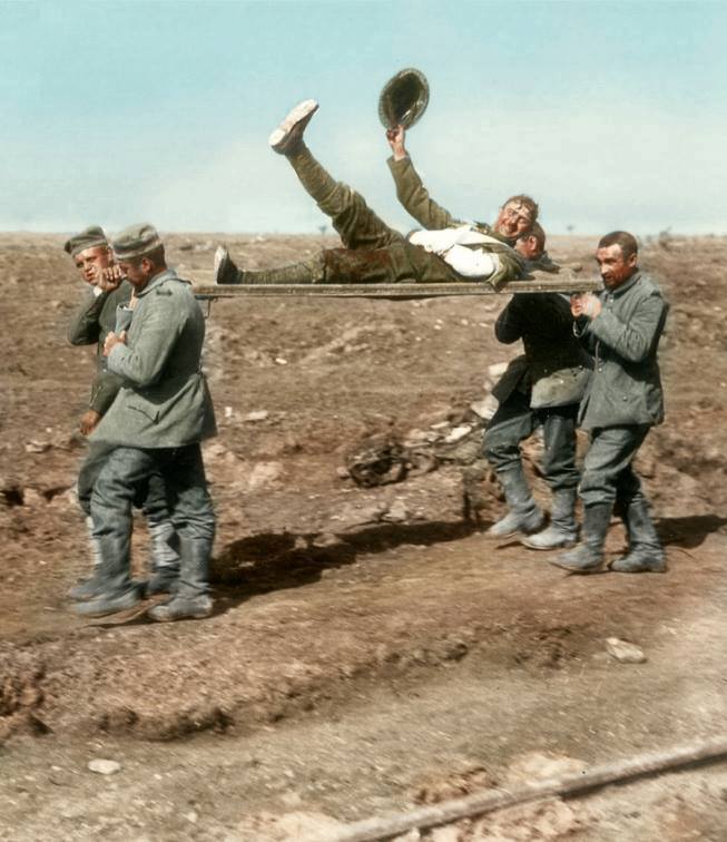 "Take me back to dear old Blighty" Battle of Flers-Courcelette. A stretcher borne wounded soldier waves his helmet (and leg) as he is carried in by German prisoners. Near Ginchy, 15th September 1916. © IWM (Q 1321) Photographer - Lt. Ernest Brooks