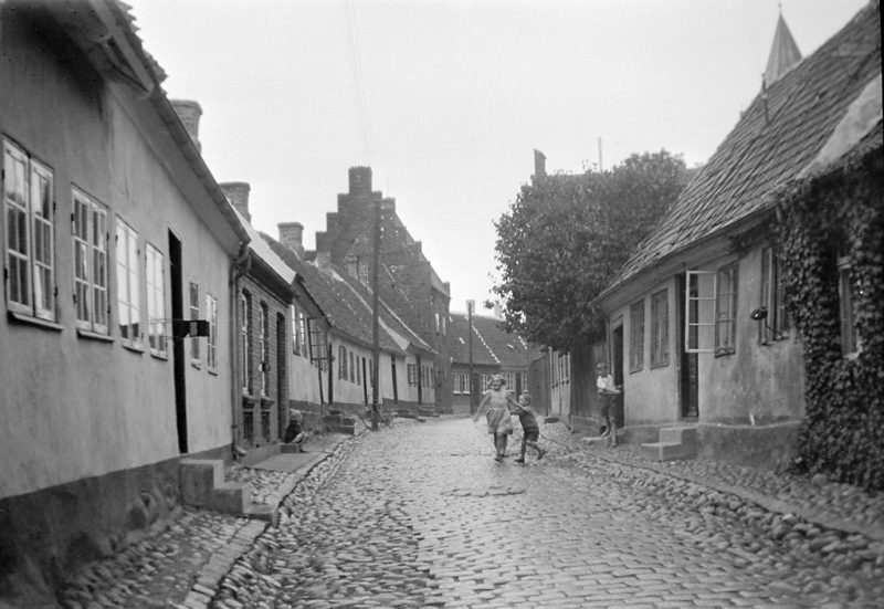 Children in Præstegade street (Priest street) in Kalundborg. In the background to the left is a medieval house with stepped gable roof
