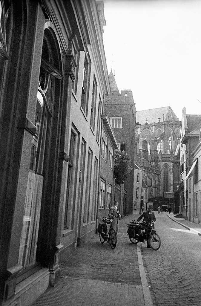 Men with bikes in a street in Utrecht, with the _Domkerk_ St. Martin's Cathedral in the background