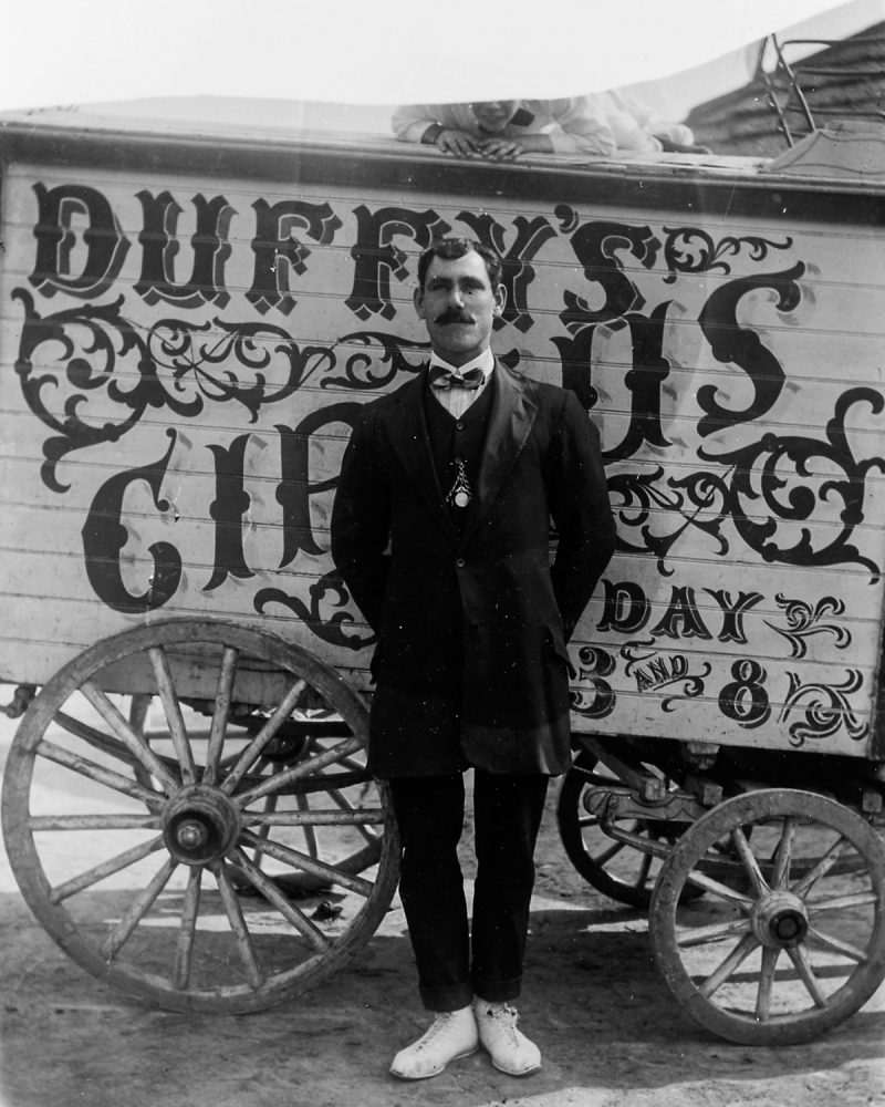 A child photobombs a man from Duffy's Circus. 1911