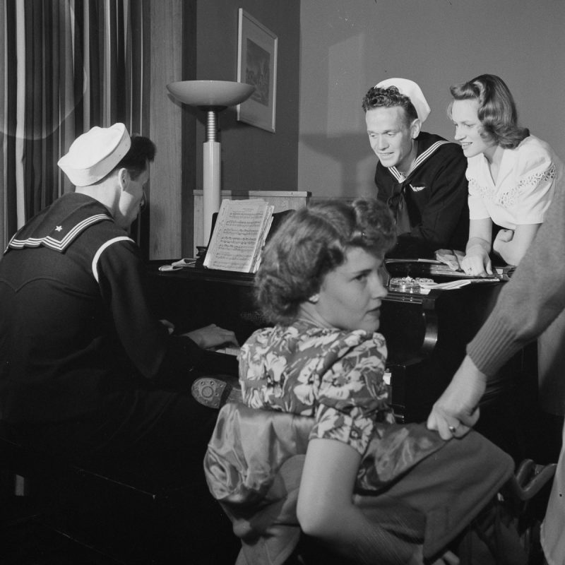 Residents-and-guests-gather-around-a-piano-in-the-main-lounge-of-Idaho-Hall