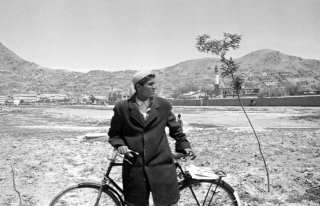 Aghan teenager standing with his bicycle outside