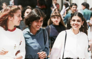 Three female students walking through a crowd