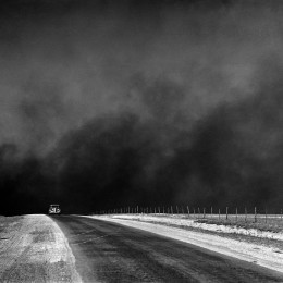 An unidentified car on a road in the Texas Panhandle with heavy clouds of dust in the sky .Source