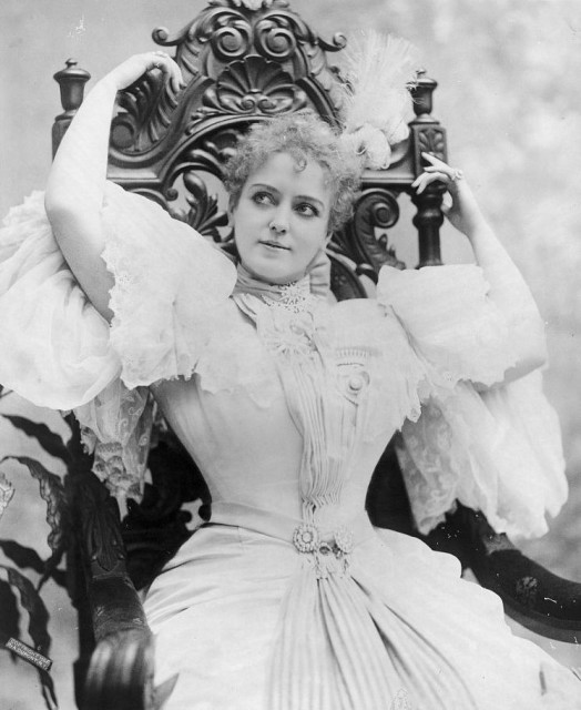 Lillian Russell, three-quarter length portrait, seated, with arms above head Source