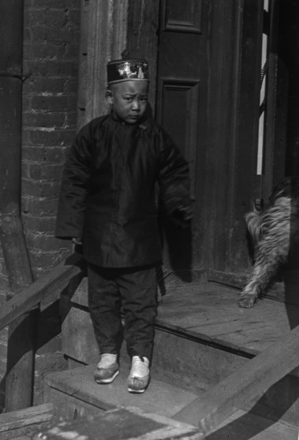 Boy standing on steps in front of a doorway, Chinatown, San Francisco 1896-1906