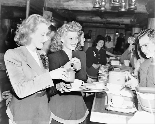 Marlene Dietrich and Rita Hayworth serving food to soldiers at the Hollywood Canteen.