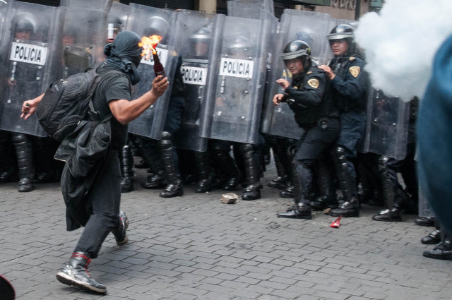 A protester in Mexico threatening to throw a cocktail at police, 2013. Source