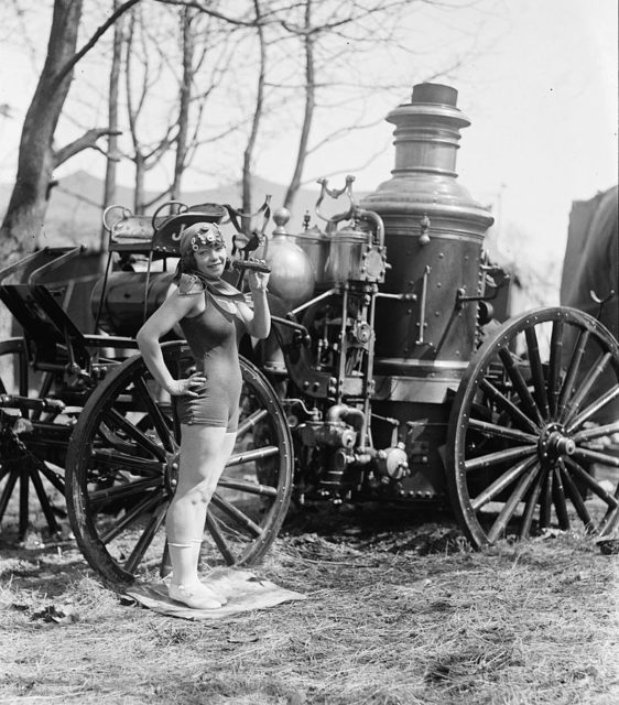 Beatrice Kyle next to a fire engine eating a pickle, 1924