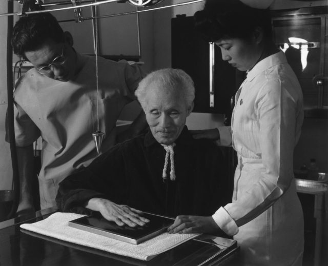 Harry Sumida, a veteran of the Spanish-American war, receives an X-ray from nurse Aiko Hamaguchi and technician Michael Yonemetsu.