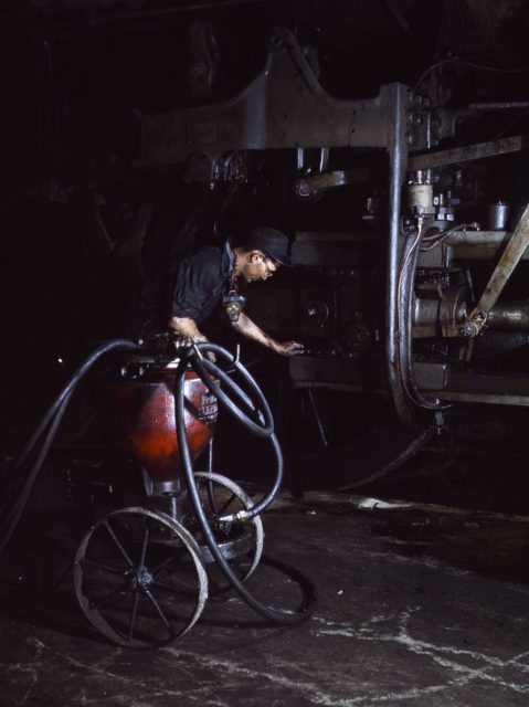 Thomas Madrigal greasing a locomotive in the roundhouse, Rock Island Railroad, Blue Island, Illinois.
