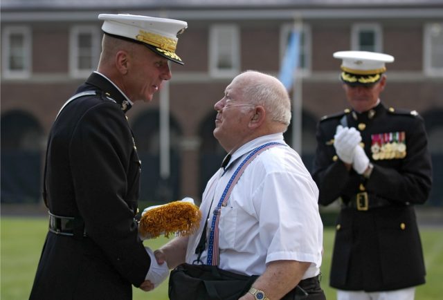 Jacklyn H. Lucas shakes hands with the Commandant of the Marine Corps Gen. Michael W. Hagee while receiving his Medal of Honor ceremonial flag during a ceremony at the Marine Barracks in Washington, D.C., Aug. 3, 2006. Source