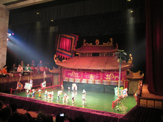 Thang Long Water Puppet Theatre in Hanoi. Spotlights and colorful flags adorn the stage and create a festive atmosphere. Source