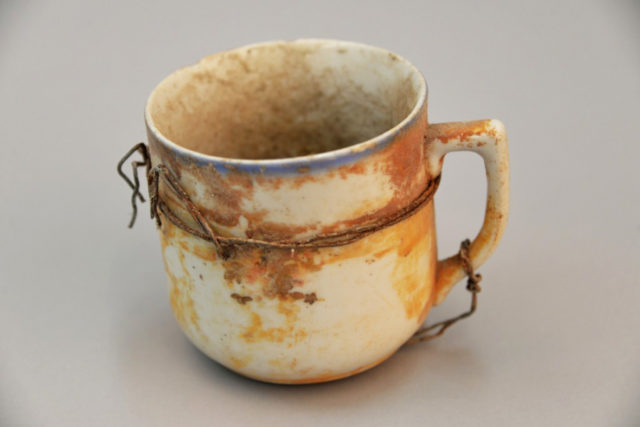 A cup reinforced with rusty wire, one of thousands of objects found in 1967 near the crematorium number 3 on the site of Nazi death camp of Auschwitz Birkenau. Photo credit: Pawel Sawicki/ Auschwitz Museum