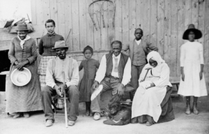 Portrait of American abolitionist Harriet Tubman (c1822 – 1913) (left) as she poses with her family, friends, and neighbors on her porch, Auburn, New York