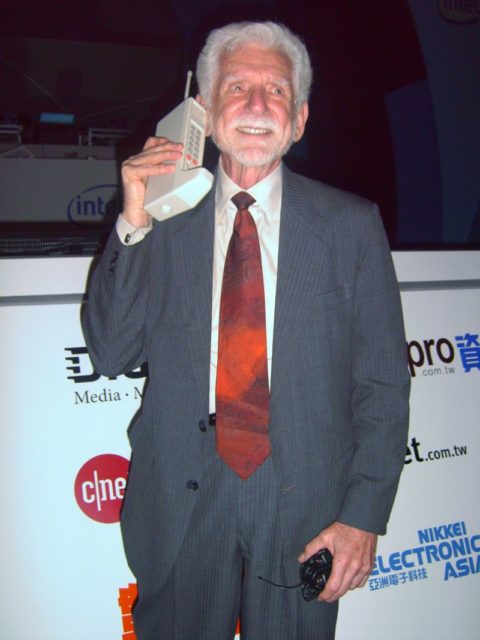 Cooper holding a DynaTAC cellphone in 2007. Photo by Rico Shen CC BY-SA 3.0