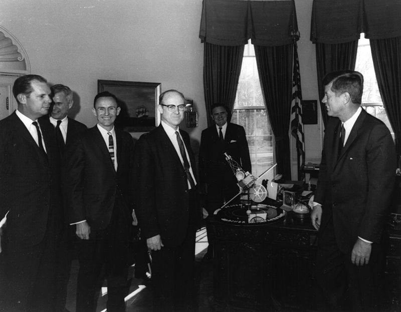 William H. Pickering, (center) JPL Director, President John F. Kennedy, (right). NASA Administrator James E. Webb (background) discussing the Mariner program, with a model presented.