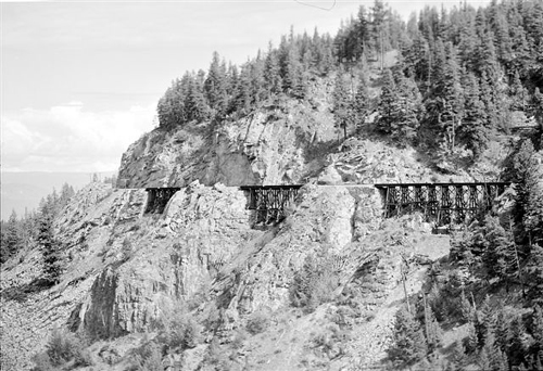 In all cases, the curvature of the rail line was minimized through long graceful curves across several trestles, and by turning the rail line gradually throughout the length of the longer trestles. The largest of the wood frame trestles, the trestle at Mile 87.9 crossing the West Canyon Creek, was a stupendous structure, 750′ long and 182′ high, and turned the rail line almost 90 degrees over its entire length at the head of the canyon