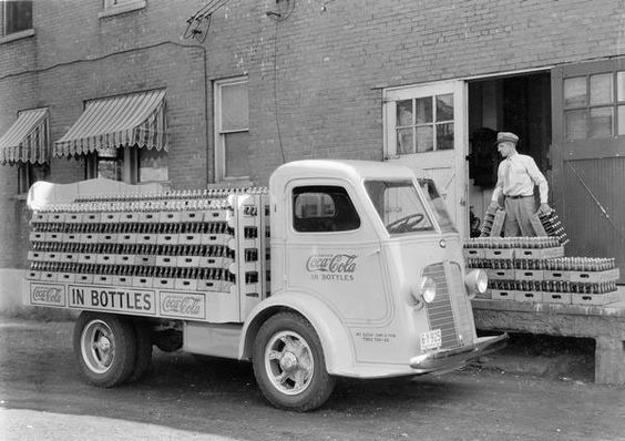 Delivery man loading bottle cases of Coca-Cola soda onto the open bed of an International C-300 delivery truck, 1936. Photo Credit