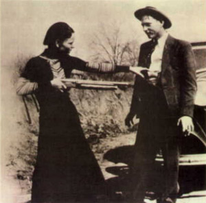 Bonnie with a shotgun reaches for officer Persell's pistol in Clyde's waistband