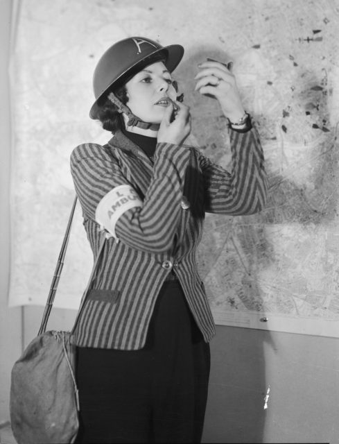 An ambulance worker in Kennington, London applies her lipstick, 1940. Photo Credit