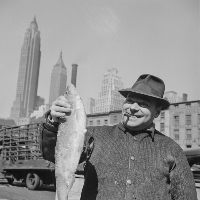 Fisherman holding a large catch at the Fulton fish market Photo Credit