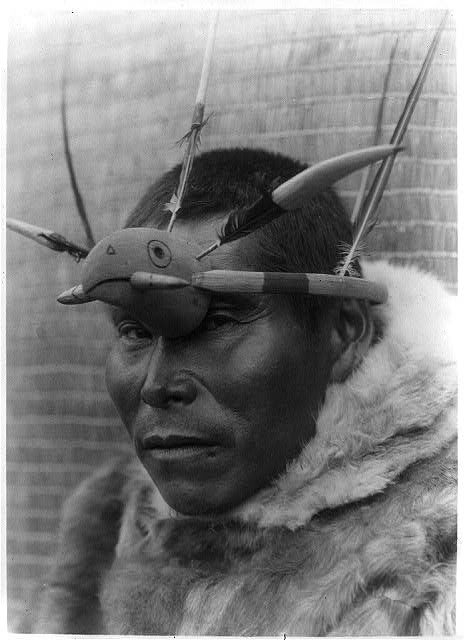 A Nunivak Cup’ig man with raven maskette. Photo Credit