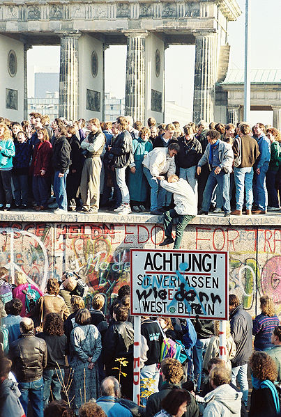 People atop the Berlin Wall near the Brandenburg Gate on 9 November 1989. . Photo Credit