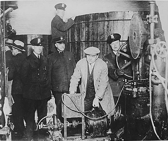 Detroit police inspecting equipment found in a clandestine brewery during the Prohibition era.