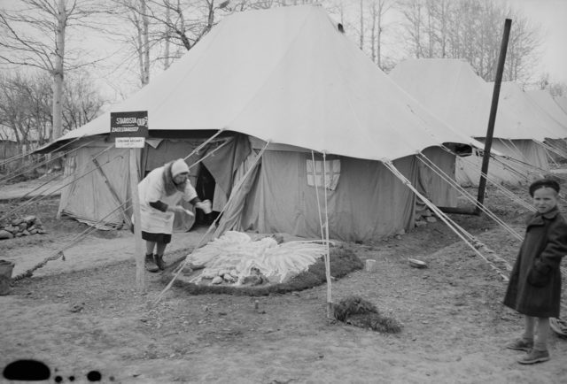 A-woman-decorates-the-front-yard-of-her-tent-with-a-Polish-eagle Photo Credit