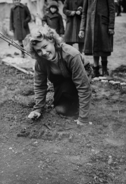 A Polish girl-landscapes-the-patch-of-earth-in-front of her tent. The photographer noted that the Poles take great pride in the cleanliness of their camp. Photo Credit