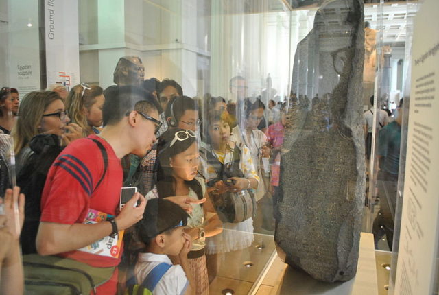 A crowd of visitors examining the Rosetta Stone at the British Museum Photo Credit